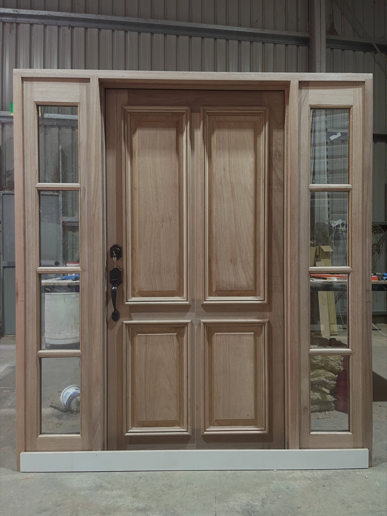 Timber entry door with glazed sidelights and brass hardware, workshop
