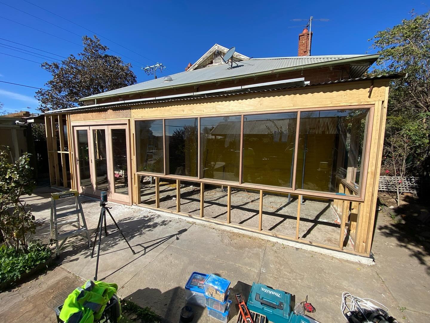 Timber-framed window wall and French doors on a home sunroom extension under construction