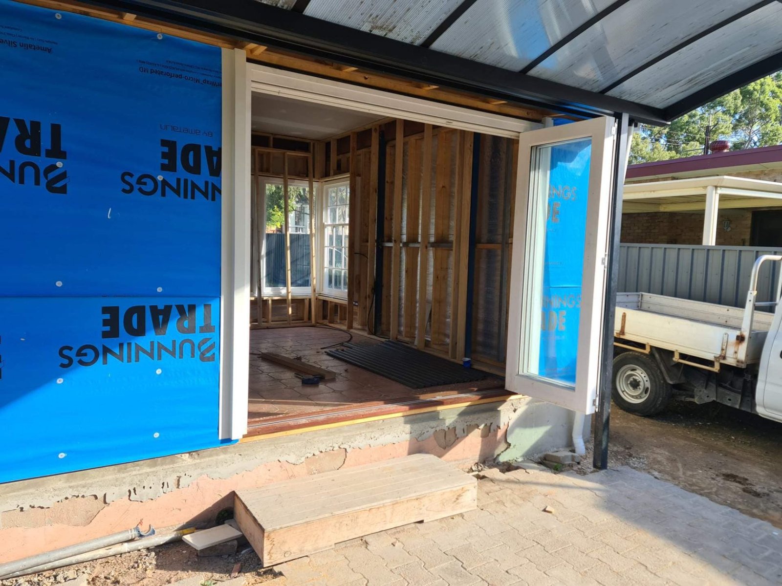 White entry door installed on a home extension under construction, timber framing visible
