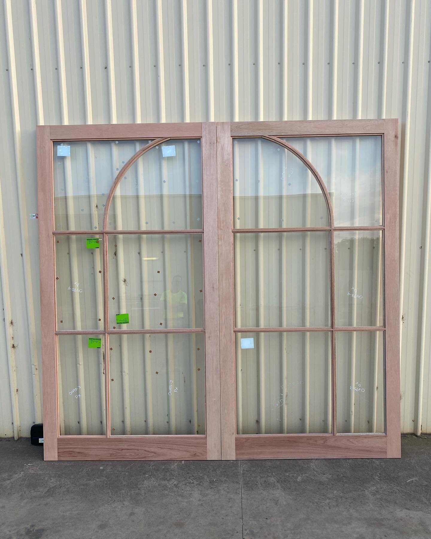 Arched-top timber French doors with multi-pane glazing, unfinished, outside the workshop