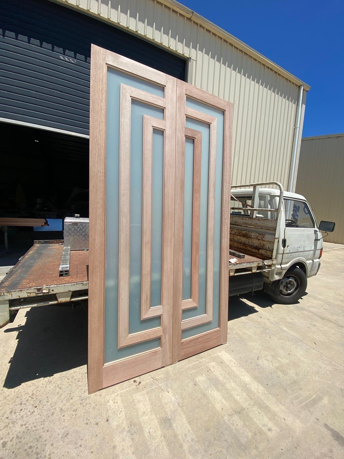 Double doors with nested rectangular frosted-glass panels and geometric timber mullions, workshop delivery