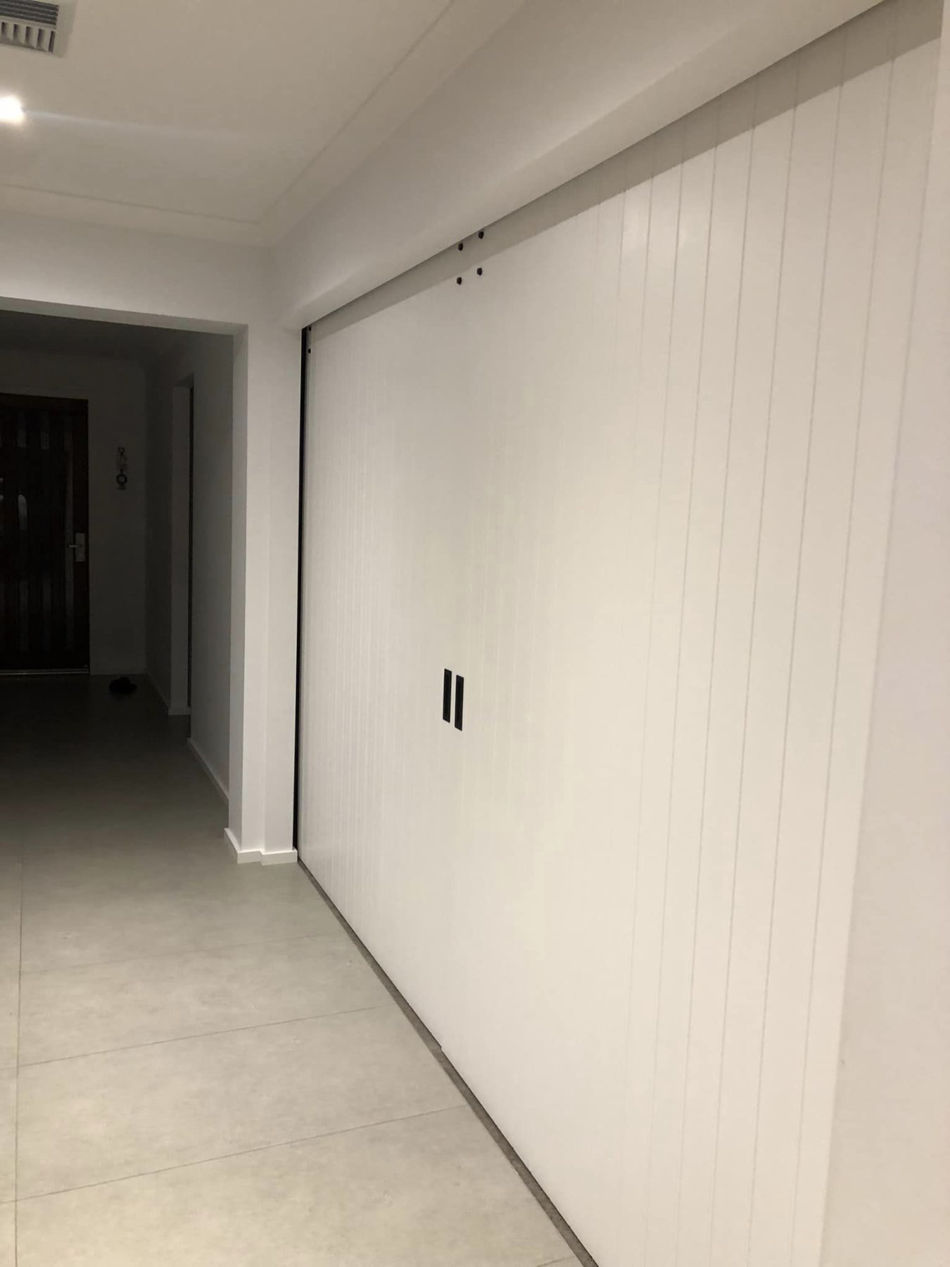 Wide white VJ-panelled sliding door concealing a walk-in storage space off the hallway