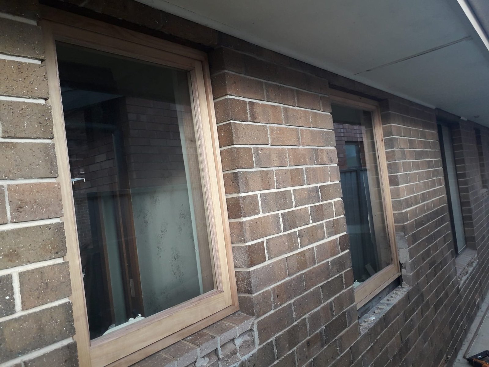 Pair of Vic Ash awning windows installed on a brick bathroom exterior wall