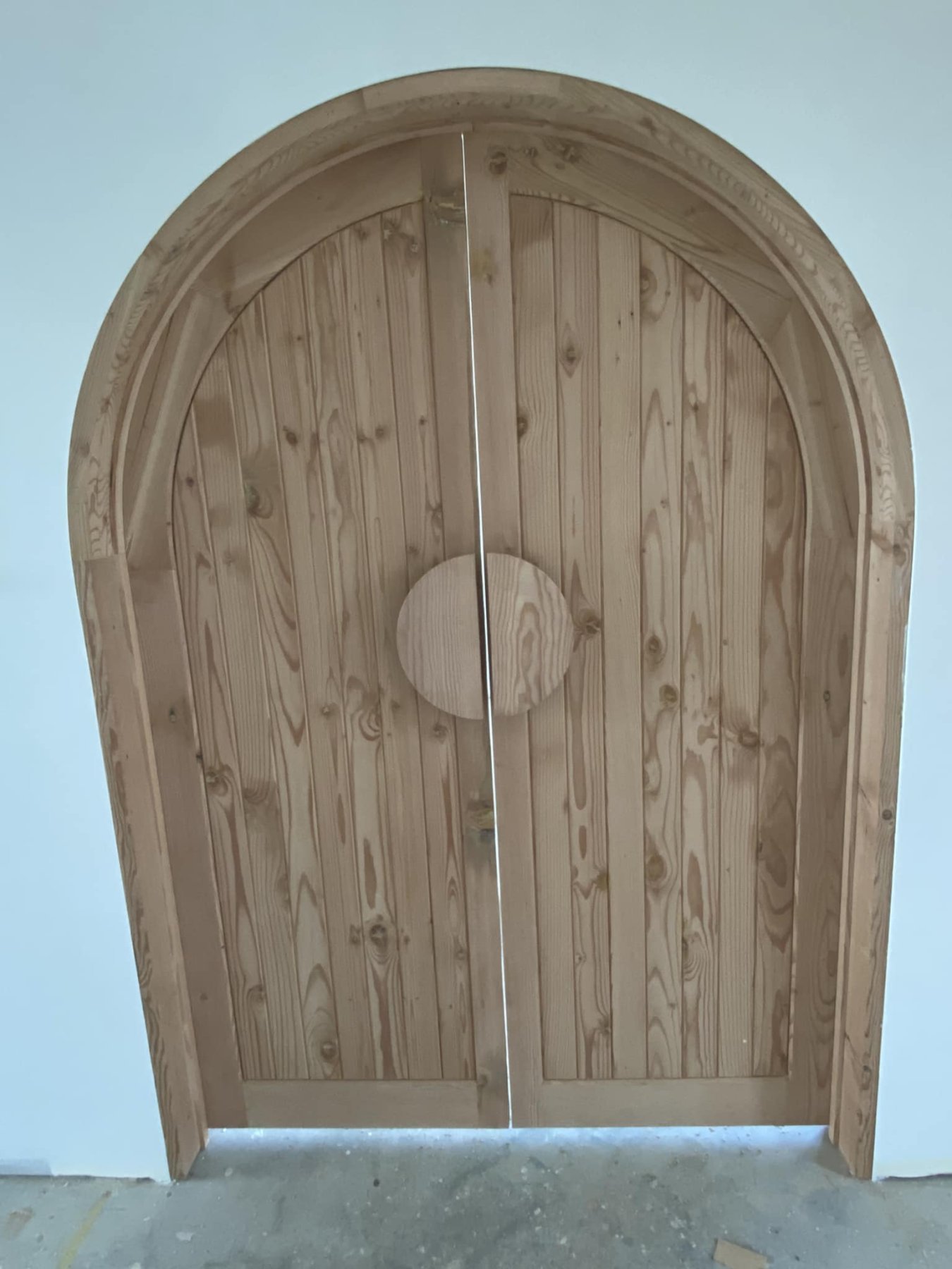 Arched double doors built from reclaimed Oregon timber, with a circular handle recess