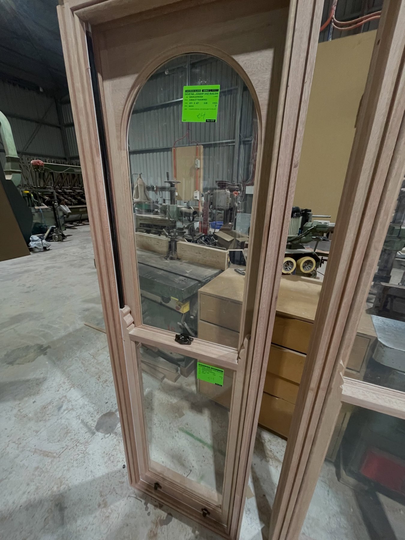 Arched-top timber window with fixed and awning sashes, workshop with supplier tags attached