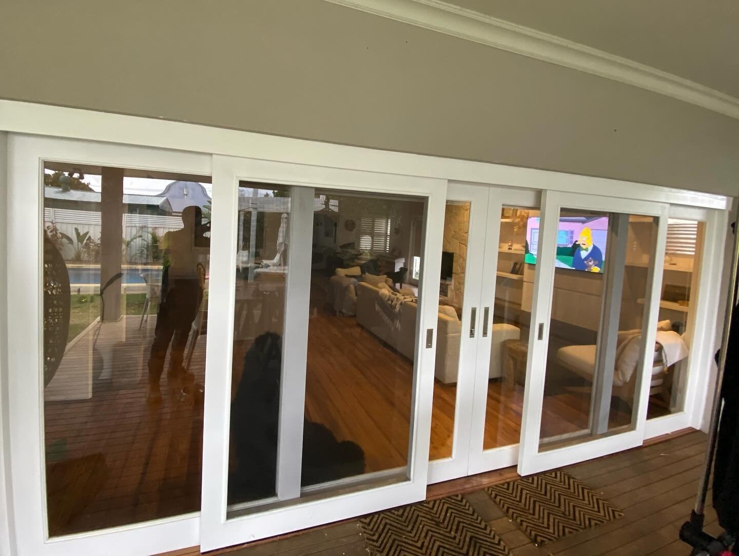 Multi-panel white sliding doors dividing a kitchen and living area, house interior