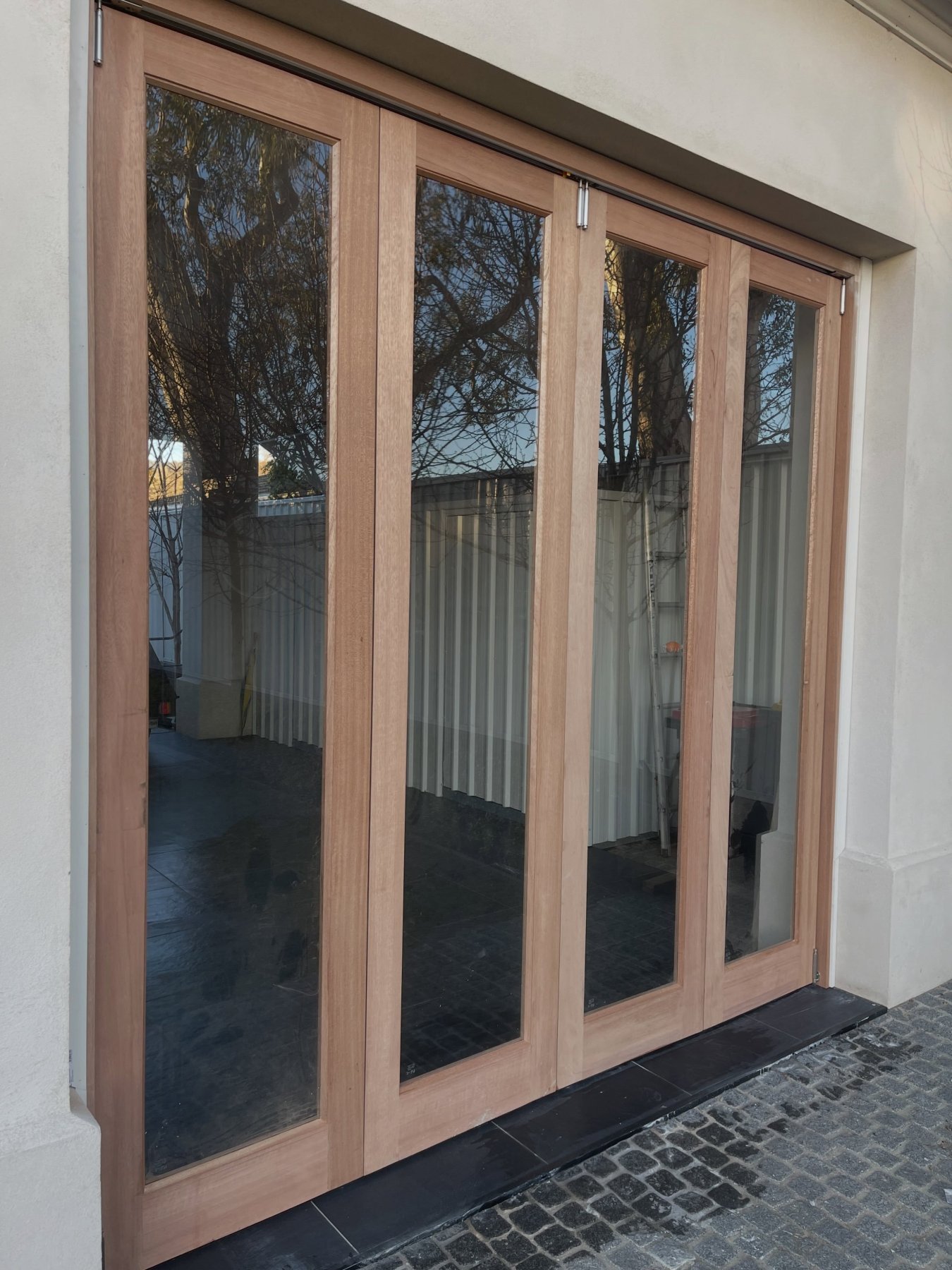 Four-panel cedar bifold door opening onto a paved outdoor patio