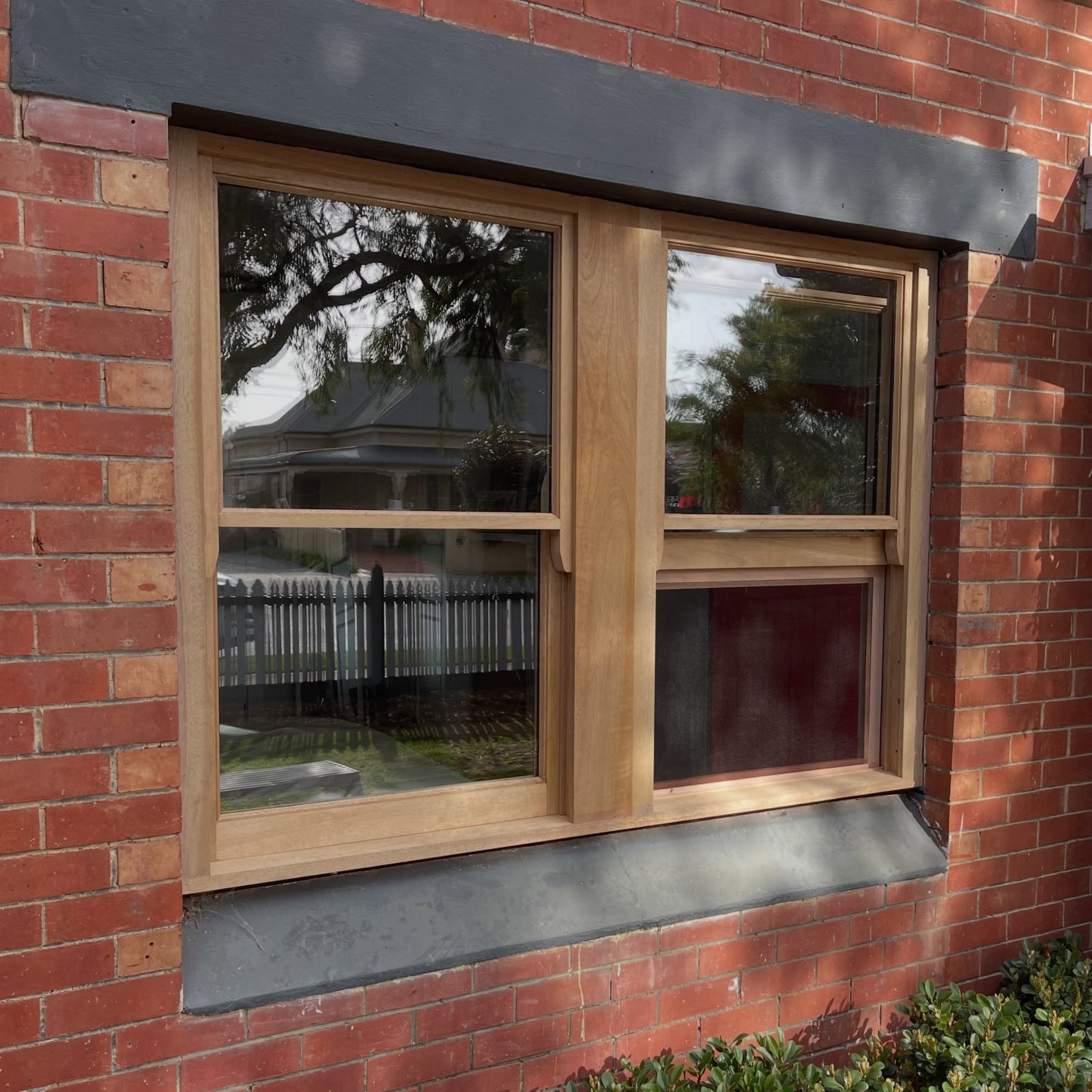 Timber double-hung sash window on a red-brick home, close-up