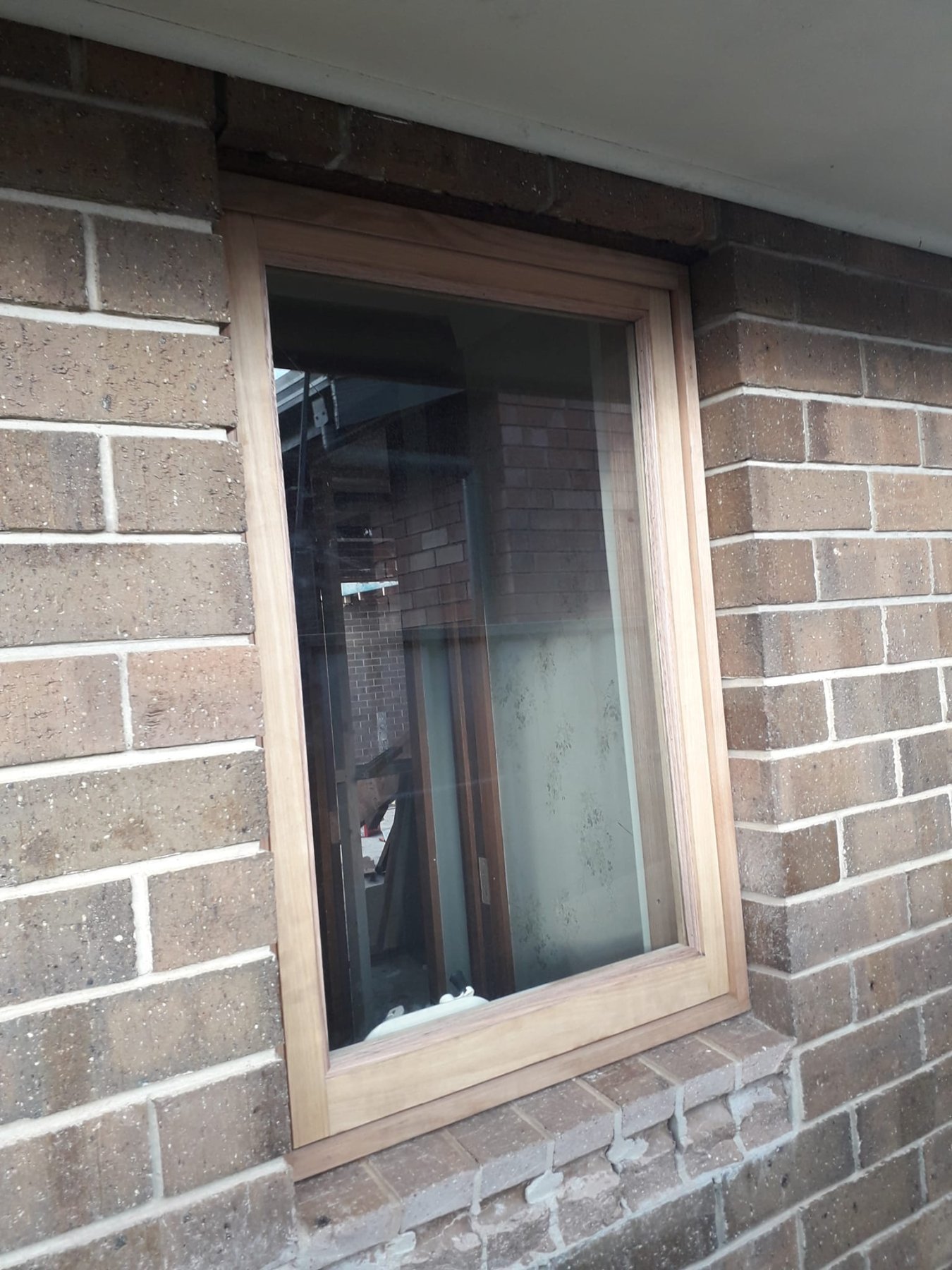 Vic Ash awning window installed in a brick bathroom wall, close-up