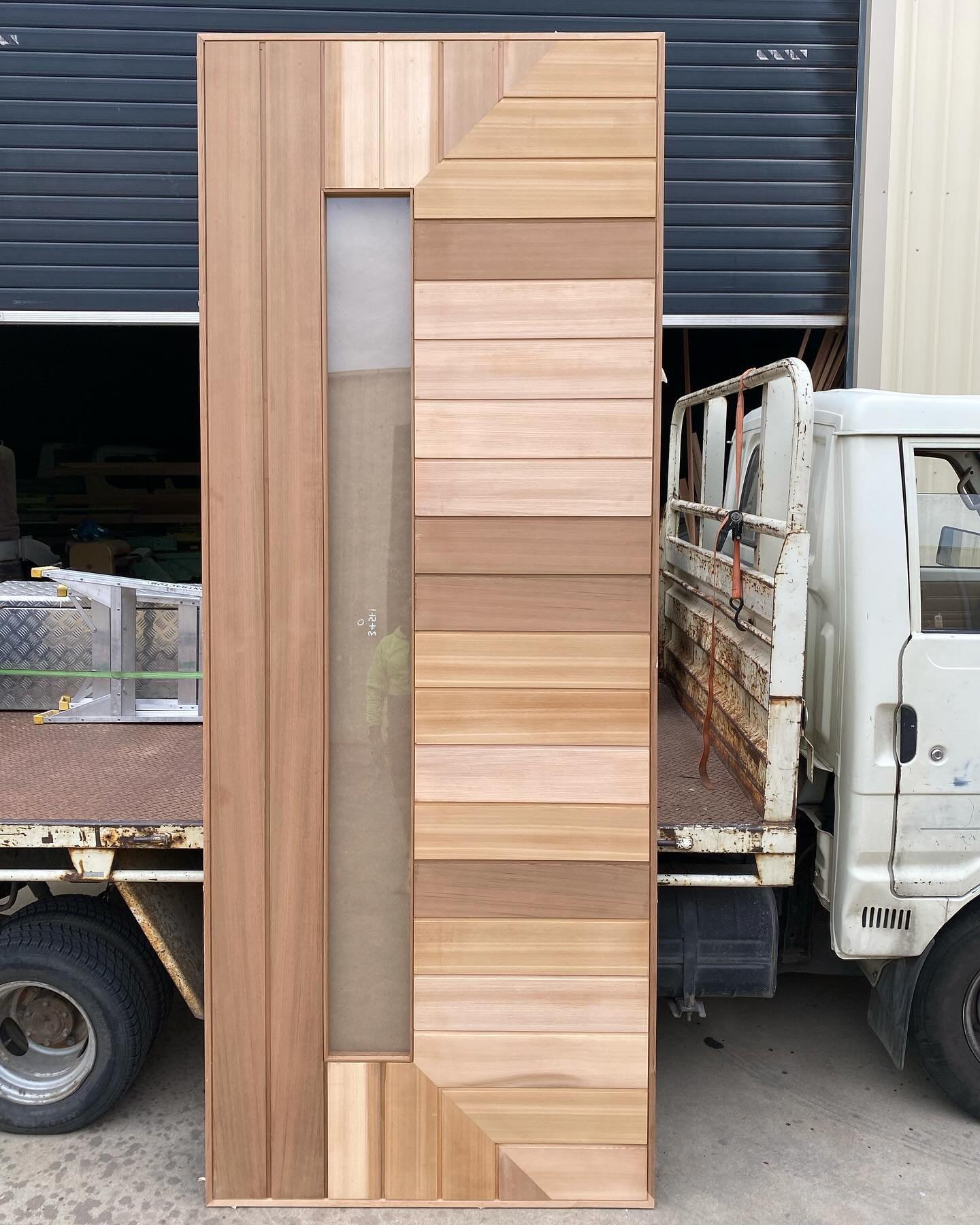 Modern horizontal-shiplap timber entry door with a narrow vertical glass sidelight