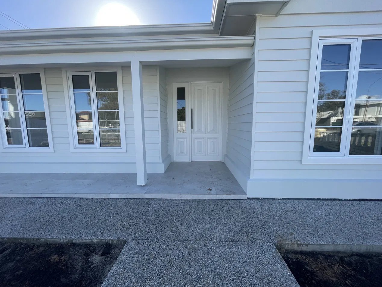 Painted timber entry door with glazed sidelight, flanked by matching feature windows