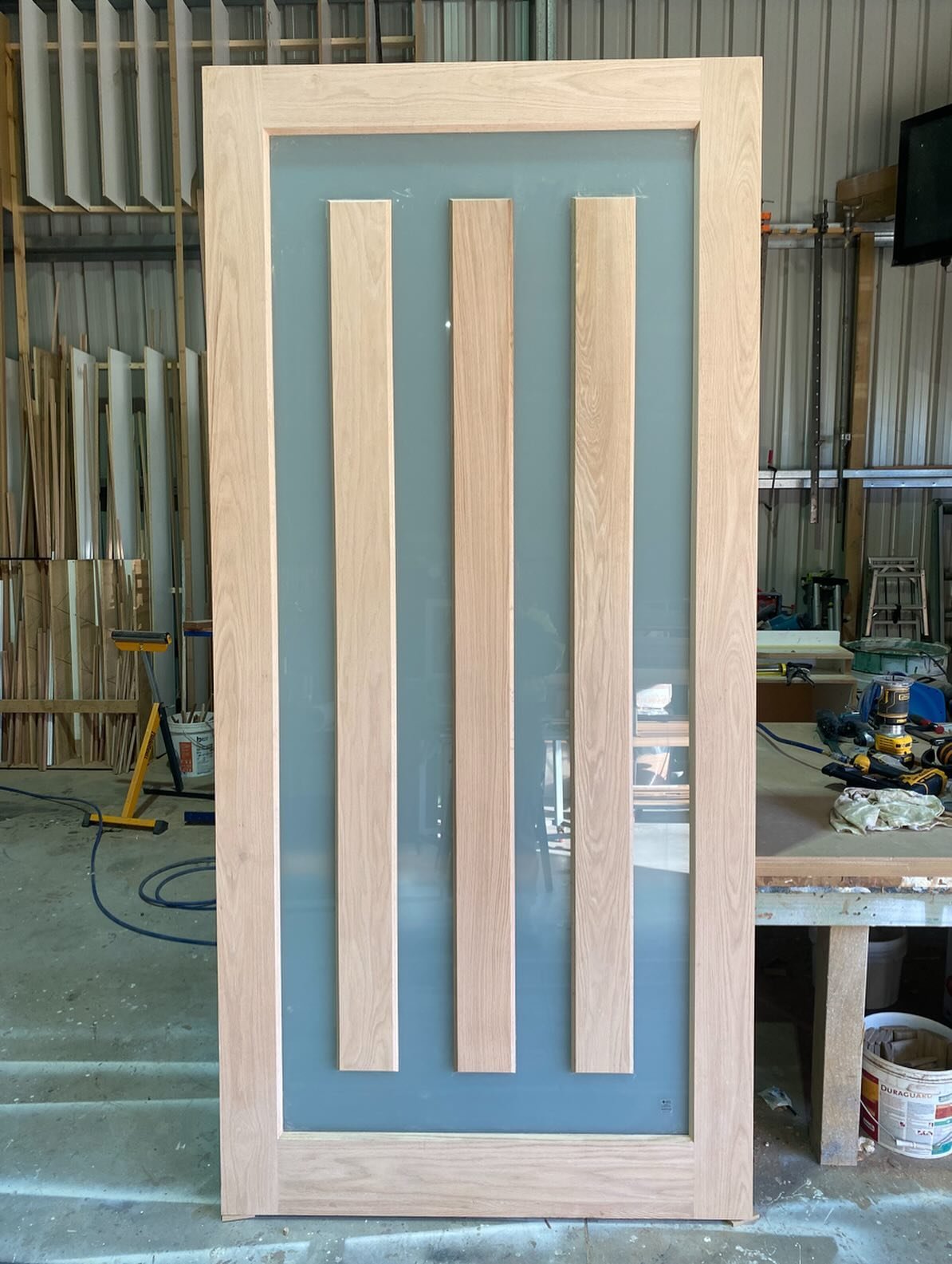 Oak-framed internal door with three vertical timber slats over a frosted glass panel