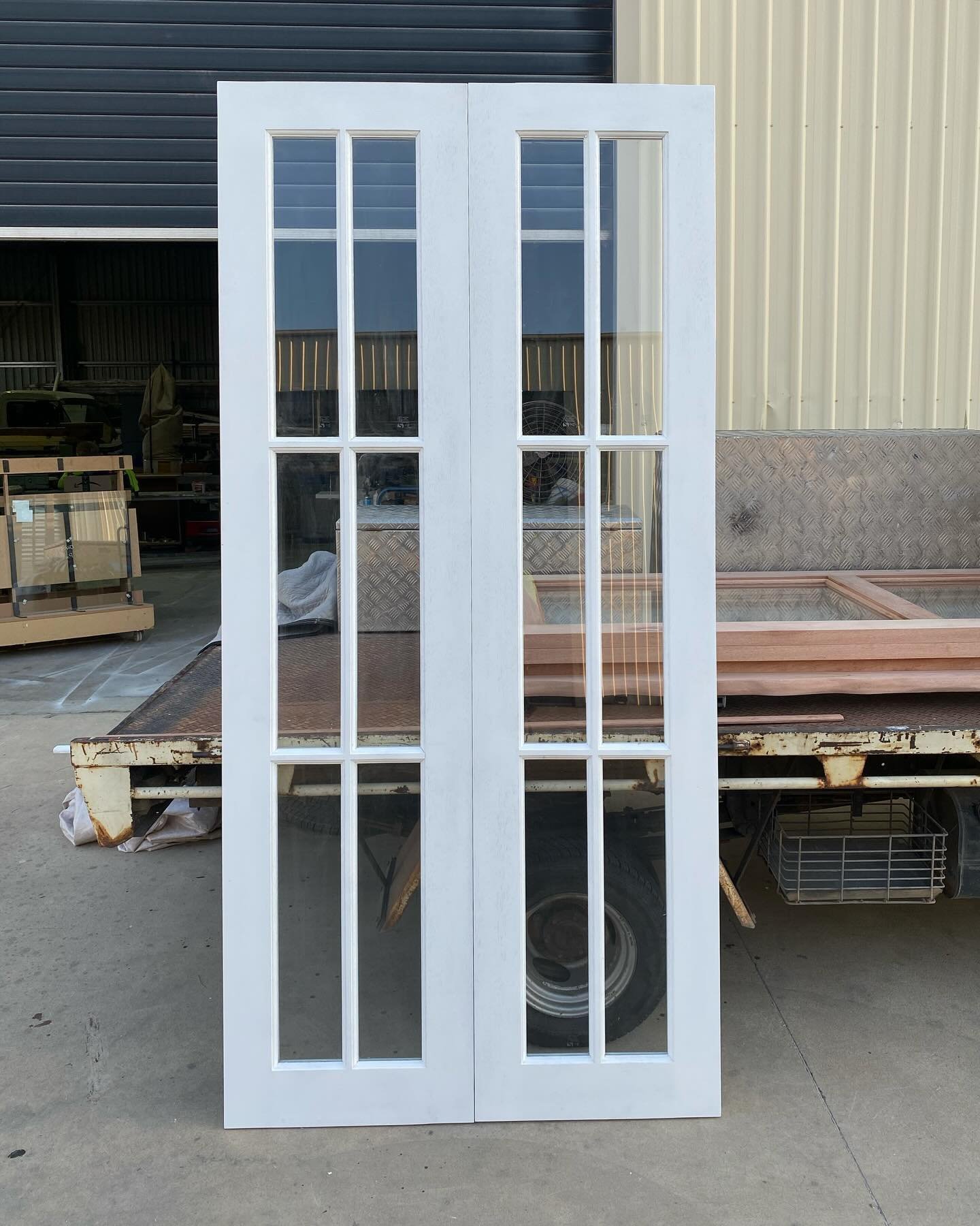 White-painted timber double doors with three-pane glazing, standing in the yard